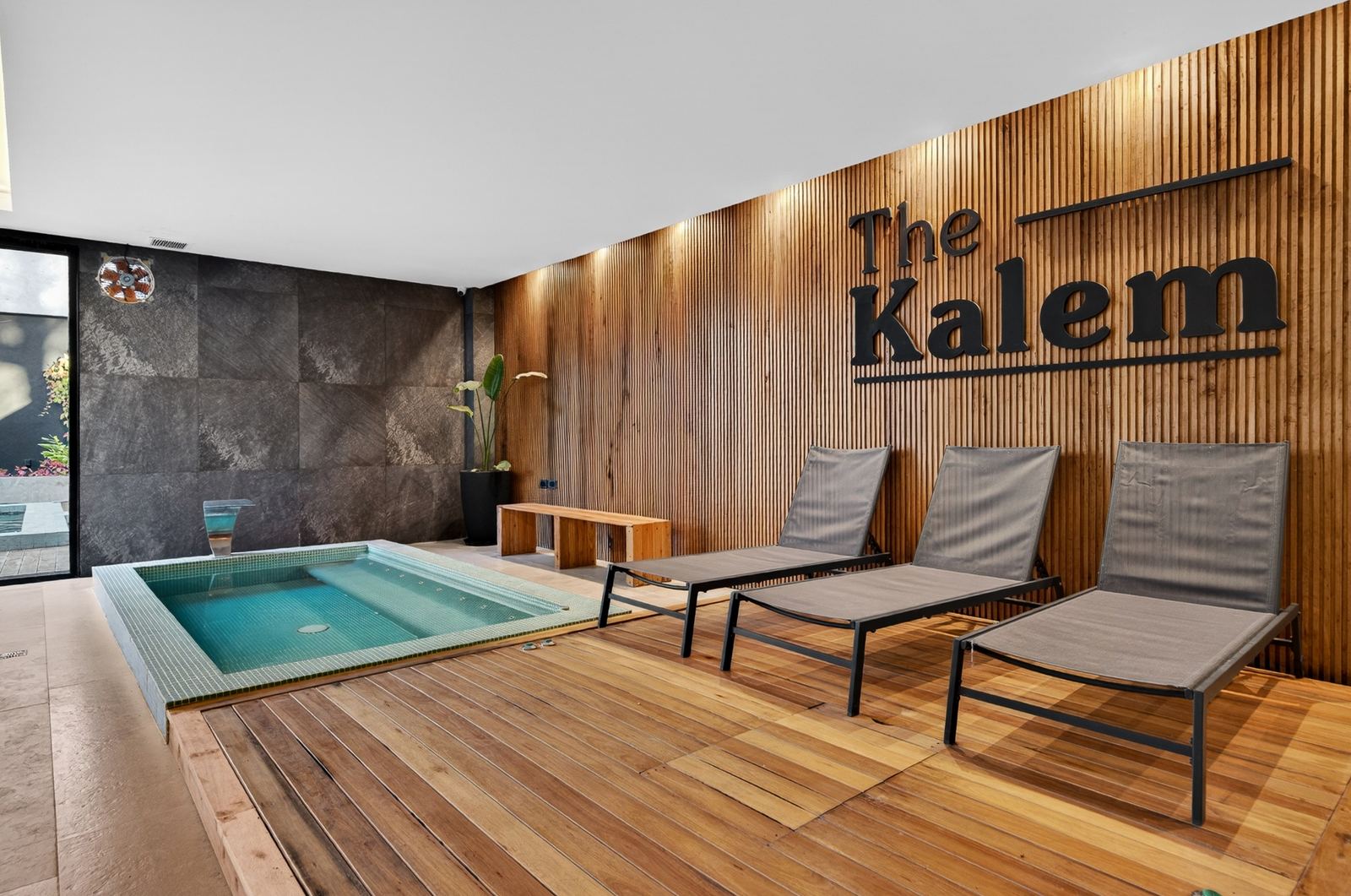 Spa con jacuzzi, reposeras y el logo de The Kalem en madera